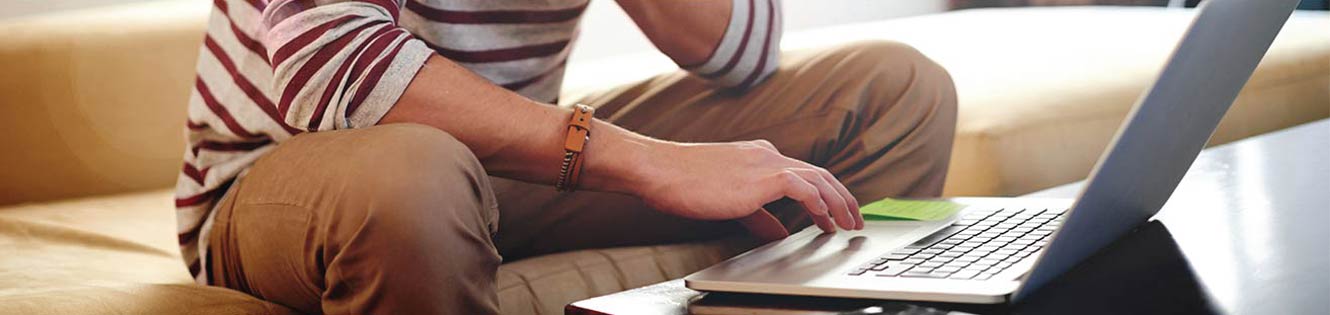 Person sitting on couch using a laptop.